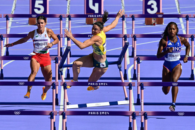 Australia's Michelle Jenneke falls as Hungary's Greta Kerekes (L) and France's Cyrena Samba-Mayela (R) compete in the women's 100m hurdles heat of the athletics event at the Paris 2024 Olympic Games at Stade de France in Saint-Denis, north of Paris, on August 7, 2024. (Photo by Martin Bernetti/AFP Photo)