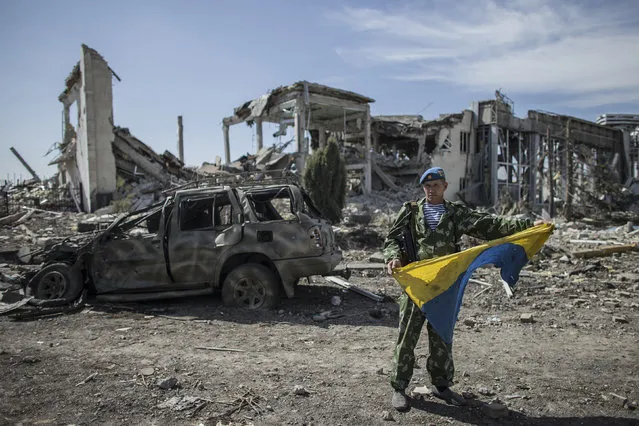 A pro-Russian rebel displays a captured Ukrainian flag at the destroyed airport in Luhansk, eastern Ukraine, September 14, 2014. Ukraine's defence minister said on Sunday that NATO countries were delivering weapons to his country to equip it to fight pro-Russian separatists and “stop” Russian President Vladimir Putin. (Photo by Marko Djurica/Reuters)