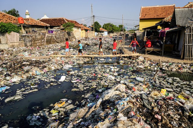 Children walk on bamboo to cross a river filled with garbage in Serang, Banten on July 17, 2024. (Photo by Dziki Oktomauliyadi/AFP Photo)