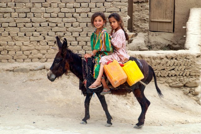 Afghan girls ride a donkey along a street in Argo district at Badakhshan province on July 30, 2024. (Photo by Omer Abrar/AFP Photo)