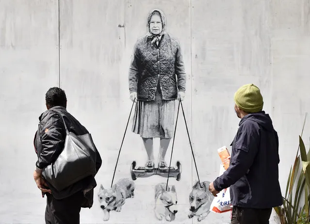 People pass a new mural depicting Britain's Queen Elizabeth II spray painted onto an external wall of a house in south-east London, Britain, 16 May 2016. The artwork is created by Banksy-style street painter “Catman”. (Photo by Hannah Mckay/EPA)