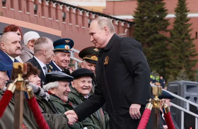 Russian President Vladimir Putin shakes hands with spectators before a military parade on Victory Day, which marks the 77th anniversary of the victory over Nazi Germany in World War Two, in Red Square in central Moscow, Russia on May 9, 2022. (Photo by Sputnik/Kremlin via Reuters)