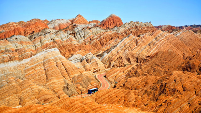 A travel bus drives through the Qicai Danxia Scenic Area, also known as Colorful Danxia Scenic Spot, at Zhangye National Geopark on August 18, 2024 in Zhangye, Gansu Province of China. (Photo by Lin Tong/VCG via Getty Images)