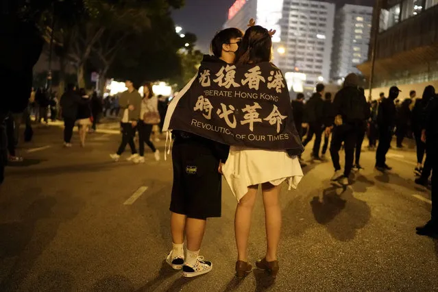 A couple kiss draped in a banner with the words “Liberate Hong Kong, Revolution of our Times” during a rally on Christmas Eve in Hong Kong on Tuesday, December 24, 2019. (Photo by Kin Cheung/AP Photo)