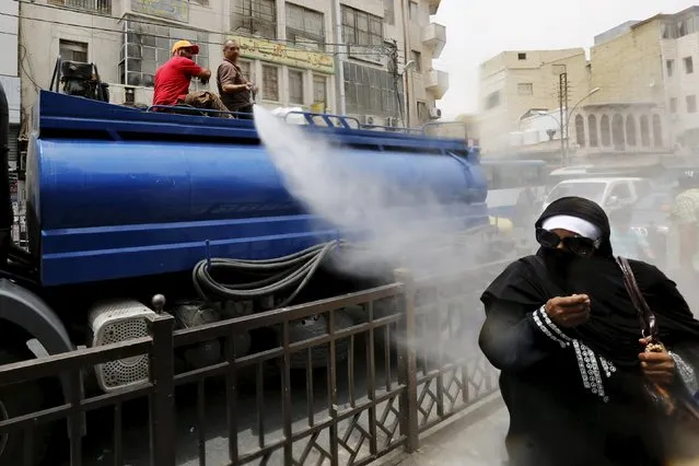 Greater Amman Municipality personnel spray people with a water sprinkler in order to cool them down as part of measures to ease the effect of a heatwave, in Amman, Jordan, August 3, 2015. (Photo by Muhammad Hamed/Reuters)