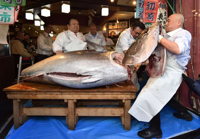Kiyoshi Kimura (L), president of Kiyomura Corp., the Tokyo-based operator of sushi restaurant chain Sushizanmai, looks on as employees slice up a bluefin tuna the company bought for 193.2 million yen (1.8 million USD) at auction at his main restaurant in Tokyo on January 5, 2020. Kiyomura Corp. made the winning bid of 1.8 million USD for a 276-kilogram bluefin tuna caught off Oma, Aomori prefecture at the first auction of the year earlier in the day at Tososu fish market. (Photo by Kazuhiro Nogi/AFP Photo)