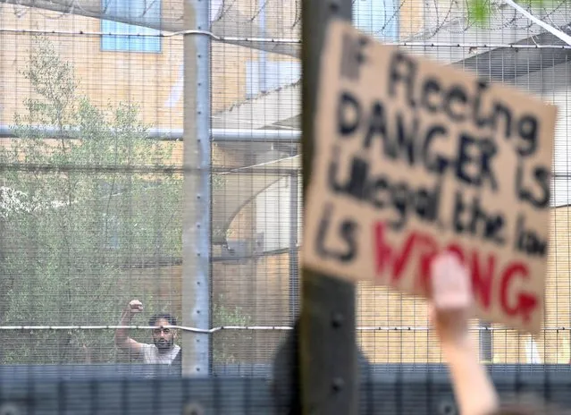A detainee inside Brook House Immigration Removal Centre gestures as demonstrators protest outside of it against a planned deportation of asylum seekers from Britain to Rwanda, at Gatwick Airport near Crawley, Britain, June 12, 2022. (Photo by Toby Melville/Reuters)