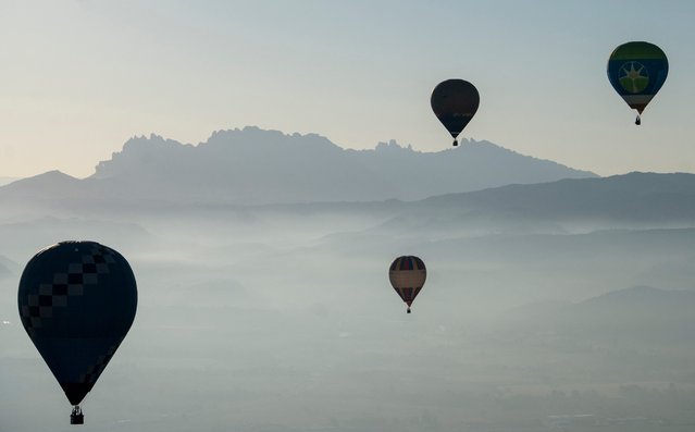 Hot-air balloons are pictured with Montserrat mountain range in the background during the European Balloon Festival in Igualada, northeastern Spain, on July 11, 2024. (Photo by Manaure Quintero/AFP Photo)