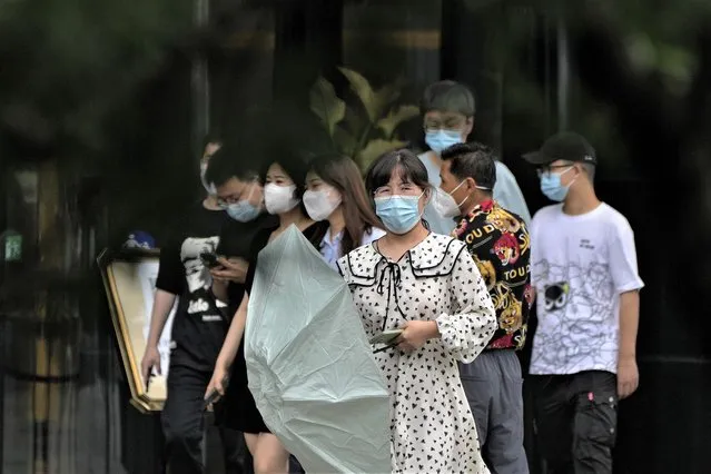 Workers wearing face masks walk out from an office building during a lunch hour break in Beijing, Wednesday, July 6, 2022. (Photo by Andy Wong/AP Photo)