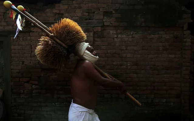 A Nepalese Hindu devotee carries water-soaked hay as part of rituals during Madhav Narayan festival in Thecho, Lalitpur, Nepal, Thursday, February 6, 2020. During this month-long festival, devotees recite Holy Scriptures dedicated to Hindu goddess Swasthani and Hindu God Lord Shiva. Unmarried women pray to get a good husband while those married pray for the longevity of their husbands by observing month long fast. (Photo by Niranjan Shrestha/AP Photo)