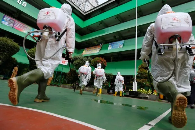 Volunteers from Indonesia's Red Cross prepare to spray disinfectant at a school closed amid the spread of coronavirus in Jakarta, Indonesia, March 16, 2020. (Photo by Willy Kurniawan/Reuters)