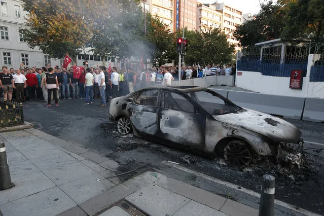 Turkish people gather and look at a burned car in Istanbul, Saturday, July 16, 2016. Turkish President Recep Tayyip Erdogan declared he was in control of the country early Saturday as government forces fought to squash a coup attempt during a night of explosions, air battles and gunfire that left dozens dead. (Photo by Emrah Gurel/AP Photo)