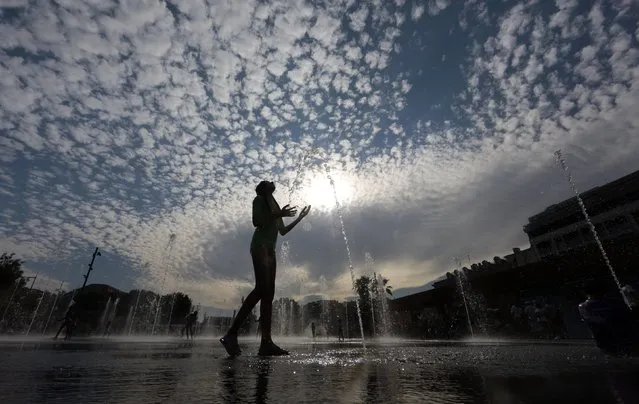 A youth cools off in a fountain during a warm and sunny summer day in Nice, August 6, 2014. (Photo by Eric Gaillard/Reuters)