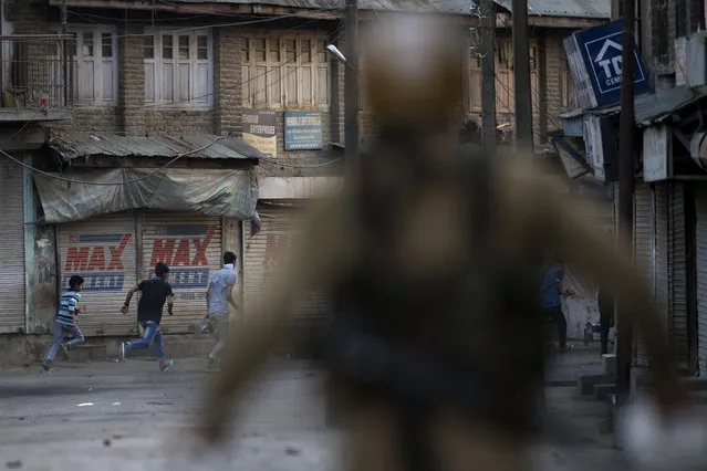 Kashmiri protesters run for cover as Indian policemen chase them during a protest in Srinagar, Indian controlled Kashmir, Tuesday, July 19, 2016. The largest street protests in recent years in the disputed region, that left dozens of people dead and hundreds injured erupted more than a week ago after Indian troops killed a popular young rebel leader. (Photo by Dar Yasin/AP Photo)