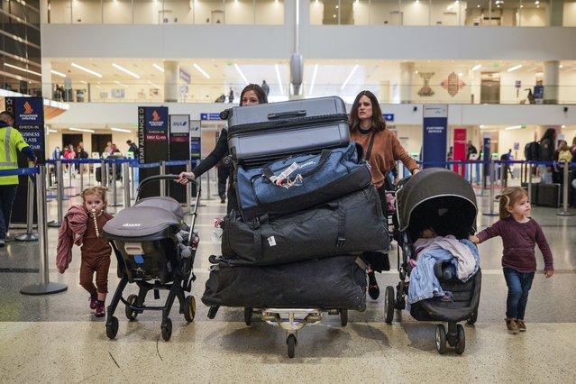 Passengers carry their luggage to check-in at the Tom Bradley International Terminal at the Los Angeles International Airport in Los Angeles, November 27, 2024. (Photo by Damian Dovarganes/AP Photo)