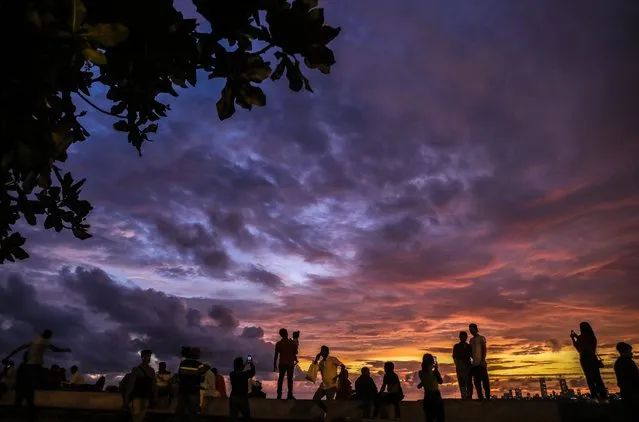 People watch the sunset along the Marine Drive promenade as monsoon clouds hover over the Arabian Sea shore in Mumbai, India, 22 June 2022. The monsoon season in India normally starts at the beginning of June and ends in September. (Photo by Divyakant Solanki/EPA/EFE)