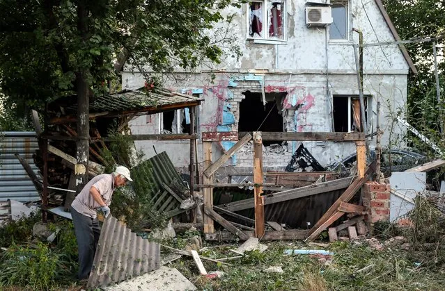 A man picks up debris damaged after Ukranian army shelling downtown of Donetsk, Ukraine, 20 August 2014. Thirty-four people have been killed in fighting between separatist militants and government troops in Ukraine's eastern Donetsk region over the past 24 hours, the local government said. Fighting was reported from the rebel-held city of Donetsk and its eastern outskirts. City authorities said that artillery battles were raging. (Photo by Sergei Ilnitsky/EPA)