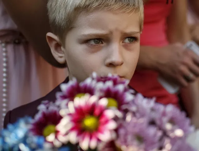 A first grader reacts as he attends a ceremony to mark the start of another school year in Kiev, Ukraine, September 1, 2015. September 1 marks the start of a new academic year for students in Ukraine. (Photo by Gleb Garanich/Reuters)