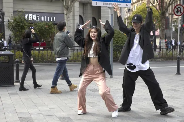 In this Wednesday, April 8, 2020, photo, youths remove their mask to record a dance routine on the streets of Wuhan in central China's Hubei province. Released from their apartments after a 2 1/2-month quarantine, residents of the city where the coronavirus pandemic began are cautiously returning to shopping and strolling in the street but say they still go out little and keep children home while they wait for schools to reopen. (Photo by Ng Han Guan/AP Photo)