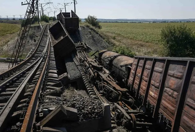Train wagons are seen on the destroyed railway bridge which collapsed during the fighting between the Ukrainian army and pro-Russian separatists, over a main road leading to the eastern Ukrainian city of Donetsk, near the village of Novobakhmutivka, north of Donetsk city, August 27, 2014. (Photo by Gleb Garanich/Reuters)