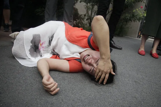 Fan Lili, the wife of imprisoned lawyer Gou Hongguo, lies on the ground in tears following an interaction with a plainclothed police officer outside the Tianjin No. 2 Intermediate People's Court in Tianjin, China, Monday, August 1, 2016. Around two dozen supporters of a prominent Chinese human rights lawyer and three activists charged with subversion protested outside a northern city court amid widespread concerns that authorities were holding their trials in secret. (Photo by Gerry Shih/AP Photo)