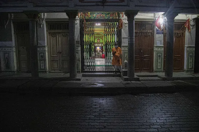 An Indian priest checks his mobile phone outside a Hindu temple during nationwide lockdown in Gauhati, India, Tuesday, May 5, 2020. (Photo by Anupam Nath/AP Photo)