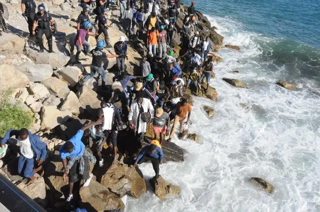 Migrants walk on the rocks as they try to get to the sea past a Police cordon in Ventimiglia, an Italian town on the border with France, Friday, August 5, 2016. Italian and French Police reportedly fired tear gas trying to prevent the migrants from reaching France. (Photo by Fabrizio Tenerelli/ANSA via AP Photo)