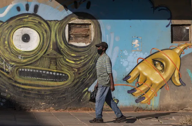 A man wearing a face mask as a precaution against the spread of the new coronavirus, walks past a mural in downtown Johannesburg, South Africa, Thursday, May 7, 2020. South Africa begun a phased easing of its strict lockdown measures on May 1, and its confirmed cases of coronavirus continue to increase as more people are being tested. (Photo by Themba Hadebe/AP Photo)