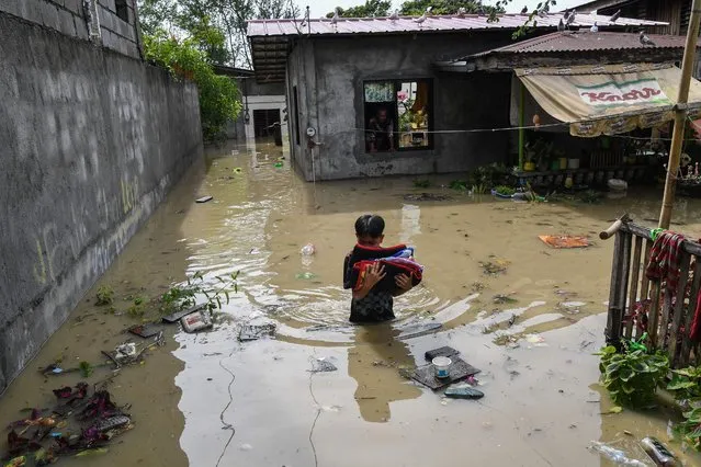 A resident carries belongings while evacuating from his submerged home in the aftermath of Super Typhoon Noru in San Ildefonso, Bulacan province on September 26, 2022. (Photo by Ted Aljibe/AFP Photo)