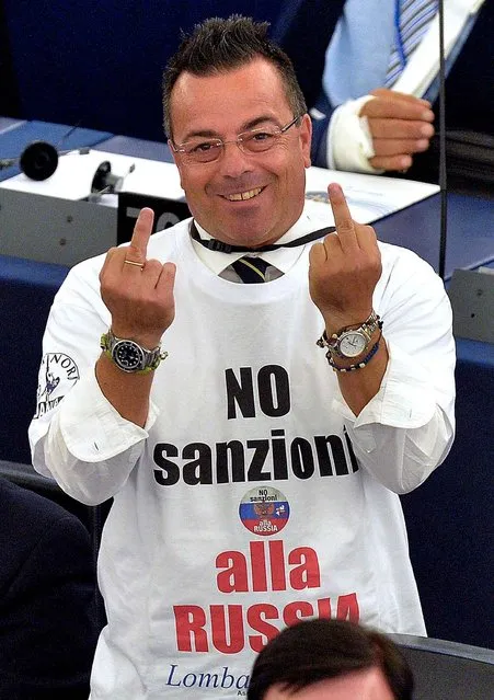 Italian non-affiliated MP Gianluca Buonanno (R), wearing a shirt reading “No sanctions to Russia”, gestures after a video-link with lawmakers in Kiev during a voting session at the European Parliament, on September 16, 2014, in Strasbourg, eastern France. The European parliament overwhelmingly voted Tuesday to ratify a landmark association pact with Ukraine, with lawmakers in Kiev who approved the deal at the same time. (Photo by Patrick Hertzog/AFP Photo)