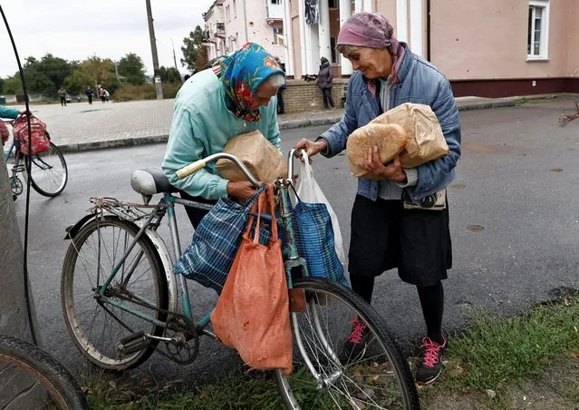 Raisa, 67, and her relative stand beside their bicycles after they received humanitarian aid, as Russia's attack on Ukraine continues, in the recently liberated town of Izium, in Kharkiv region, Ukraine on September 27, 2022. (Photo by Zohra Bensemra/Reuters)