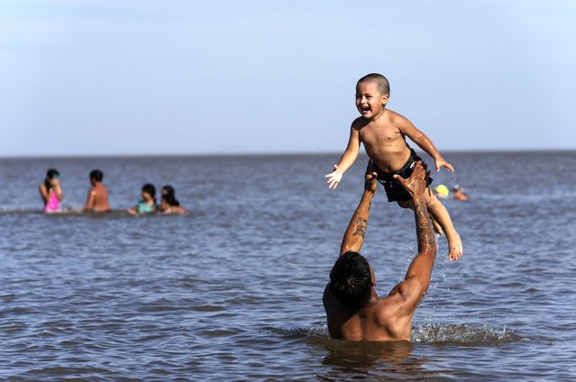Eduardo Lesse lifts up his son Damian as they play in the waters of the Rio de la Plata in Buenos Aires, Argentina, February 10, 2025. (Photo by Rodrigo Abd/AP Photo)