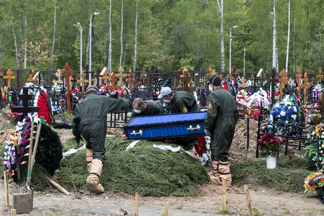 In this May 26, 2020, file photo, grave diggers wearing protective suits carry a coffin of a COVID-19 victim for burial in the section of a cemetery reserved for coronavirus victims, outside Moscow, Russia. The way Russia counts fatalities during the coronavirus pandemic could be one reason why its official death toll is far below many other countries, even as it has reported at least 511,000 infections, behind only the United States and Brazil. (Photo by Pavel Golovkin/AP Photo/File)