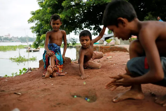Boys play with marble balls beside a road in Dhaka, Bangladesh August 1, 2016. (Photo by Mohammad Ponir Hossain/Reuters)