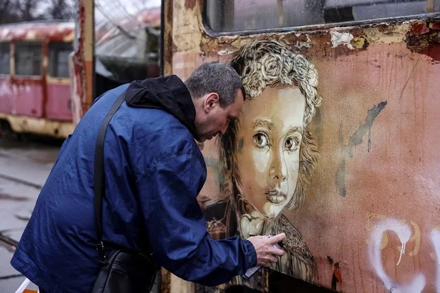 French street-artist  Christian Guemy, known as C215, paints one of his works next to a metro station and food market that were badly damaged by a Russian strike in Kyiv on April 1, 2022. (Photo by Ronaldo Schemidt/AFP Photo)