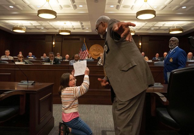 Emma Wilkins, a 10-year-old who was kneeling down in front of state lawmakers and chanting “stop attacking my friends”, is asked to go back to her seat as a House committee votes on a bill in Nashville, Tennessee, on Wednesday, March 26, 2025. The committee approved a bill that would let schools block undocumented children from enrolling, according to The Tennessean. (Photo by Nicole Hester/The Tennessean/USA Today Network/Imagn Images)