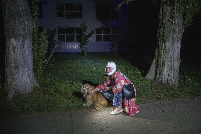 An injured woman sits with her dog near a house destroyed by a Russian airstrike in a residential neighborhood in Kyiv, Ukraine, on Thursday, April 24, 2025. (Photo by Evgeniy Maloletka/AP Photo)