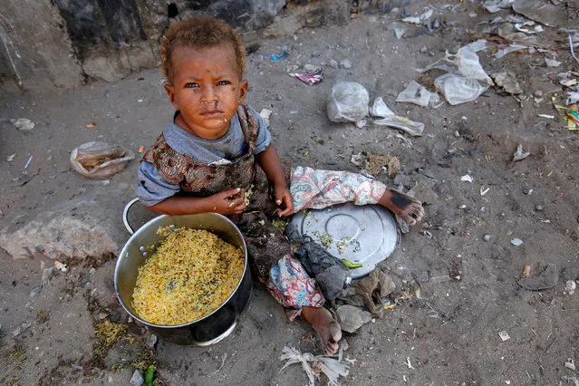 A girl displaced by the war in the northwestern areas of Yemen eats outside her family's makeshift hut on a street in the Red Sea port city of Hodeida, Yemen December 25, 2017. (Photo by Abduljabbar Zeyad/Reuters)