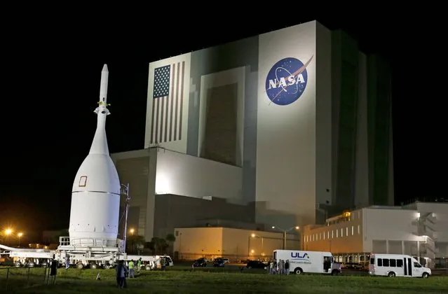 The Orion Spacecraft moves by the Vehicle Assembly Building on its approximately 22 mile journey from the Launch Abort System Facility at the Kennedy Space Center to Space Launch Complex 37B at the Cape Canaveral Air Force Station, Tuesday, November 11, 2014, in Cape Canaveral, Fla. The test flight for Orion is scheduled to launch on December 4. (Photo by John Raoux/AP Photo)