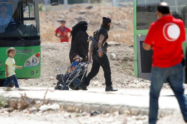 A Syrian rebel and his family walk towards a bus to evacuate the besieged Waer district in the central Syrian city of Homs, after a local agreement reached between rebels and Syria's army, Syria September 22, 2016. (Photo by Omar Sanadiki/Reuters)