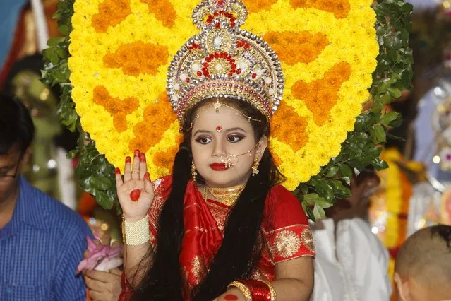 A Hindu virgin girl dressed as "Kumari" sits a on dais to be worshipped as a symbol of purity and representative of Devi Durga during the celebration of the Kumari Puja, in Dhaka’s Ramakrishna Mission, Bangladesh October 21, 2015. Kumari Puja is a part of biggest Hindu festival Durga Puja. Hindus believe that the goddess Durga symbolises power and the triumph of good over evil. (Photo by Ashikur Rahman/Reuters)