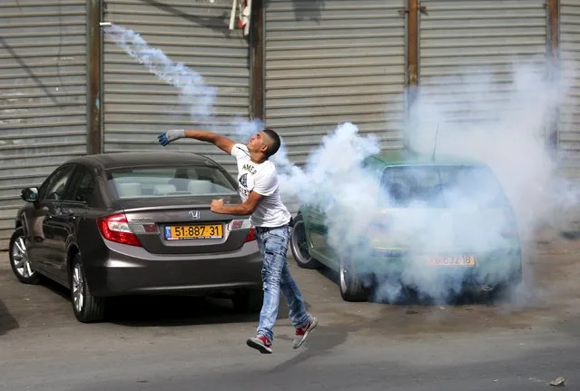 A Palestinian protester hurls back a tear gas canister fired by Israeli troops during clashes in the West Bank town of Al-Ram, near Jerusalem October 22, 2015. Nine Israelis have been killed in Palestinian stabbings, shootings and vehicle attacks since the start of October. Forty-nine Palestinians, including 25 assailants, among them children, have been killed in attacks and during anti-Israeli protests. (Photo by Mohamad Torokman/Reuters)