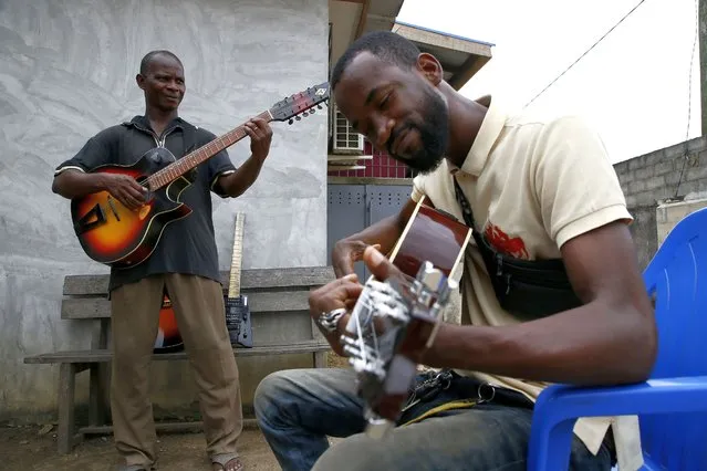 Adicko Pierre, 62, an Ivorian luthier (L) plays a guitar made by him, in the yard of his workshop  in Abobo, a district of Abidjan, Ivory Coast on September 30, 2020, a day before International Music Day. International Music Day is celebrated every year on October 1. It was established in 1975 by the International Music Council (CIM), itself founded in 1949 by UNESCO. Music plays an essential role for many people and is a powerful vector for intercultural rapprochement. The International Day dedicated to it aims primarily to highlight its importance and that of musicians on a global scale, and to promote the social value that its status as a common language confers on it as a factor of peace and understanding. (Photo by Legnan Koula/EPA/EFE/Rex Features/Shutterstock)