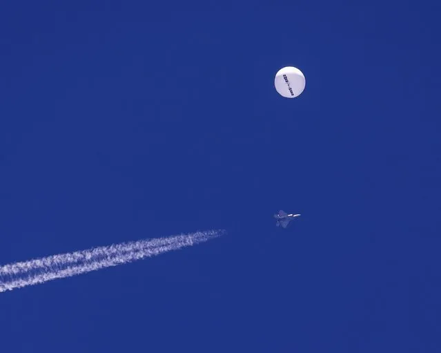In this photo provided by Chad Fish, a large balloon drifts above the Atlantic Ocean, just off the coast of South Carolina, with a fighter jet and its contrail seen below it, Saturday, February 4, 2023. The balloon was struck by a missile from an F-22 fighter just off Myrtle Beach, fascinating sky-watchers across a populous area known as the Grand Strand for its miles of beaches that draw retirees and vacationers. (Phoot by Chad Fish via AP Photo)