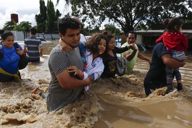 People help eachother wade through a flooded street in the aftermath of Hurricane Eta in Jerusalen, Honduras, Thursday, November 5, 2020. (Photo by Delmer Martinez/AP Photo)