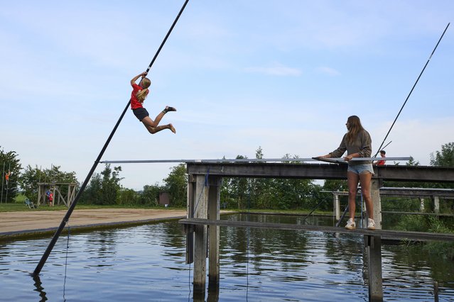 A female athlete jumps before climbing up a long carbon pole to jump across a body of water during a Fierljeppen competition in Kockengen, Netherlands, Wednesday, August 27, 2025. (Photo by Peter Dejong/AP Photo)