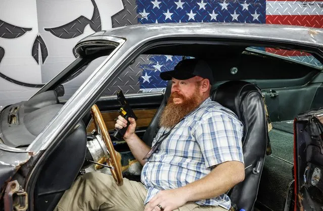 An attendee holds a weapon as he sits in a car from the movie “John Wick”, at the National Rifle Association (NRA) annual convention in Indianapolis, Indiana, U.S., April 15, 2023. (Photo by Evelyn Hockstein/Reuters)