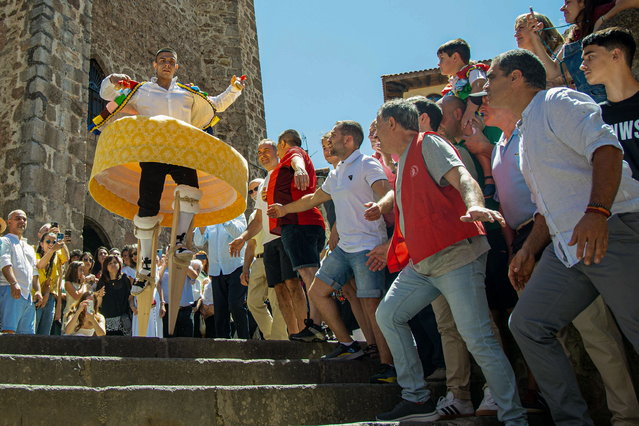 A resident, wearing a traditional costume and walking on stilts, takes part in a 'colorful dance' down steps as part of a festival called “The Anguiano Dancers” in Anguiano, La Rioja, northern Spain, 22 July 2024. The dancers walk down a slope, turning like a human spinning top onto 45-centimeter-high stilts to worship the town's patron, Mary Magdalene, in a tradition dating back to 1603. (Photo by Raquel Manzanares/EPA)
