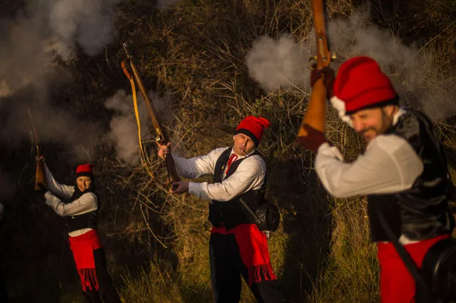 “Galejadors” fire they muskets during “La Festa del Pi” (The Festival of the Pine) in the village of Centelles on December 30, 2014 in Barcelona, Spain. Early in the morning men and women born in Centelles, who are named “Galejadors” wear their traditional costume with the Catalan red hat known as “Barretina” and carry their shooting muskets as they walk into the forest to chop down a pine tree, load it on an ox cart and take it to the church in the village. There the pine tree is decorated with five bouquets of apples and wafers and hung inside a church until January 6. (Photo by David Ramos/Getty Images)