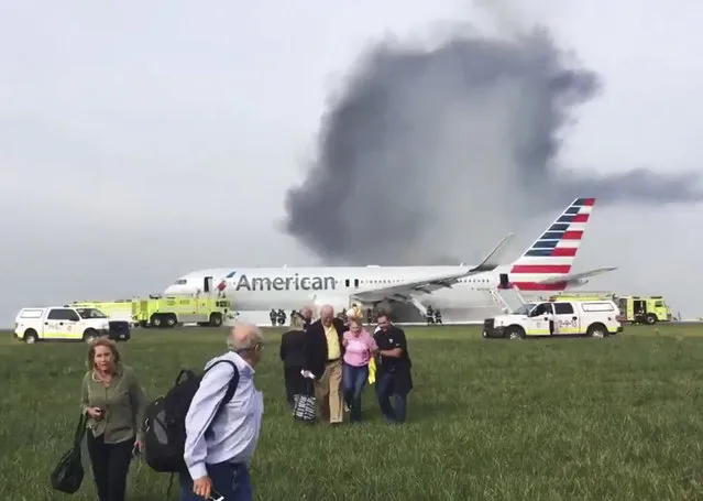 In this photo provided by passenger Jose Castillo, fellow passengers walk away from a burning American Airlines jet that aborted takeoff and caught fire on the runway at Chicago's O'Hare International Airport on Friday, October 28, 2016. Pilots on Flight 383 bound for Miami reported an engine-related mechanical issue, according to an airline spokeswoman. (Photo by Jose Castillo via AP Photo)